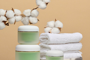 Green cosmetic jars, stack of white towels and branches of natur, a Beauty & Fashion Photo by ndanko