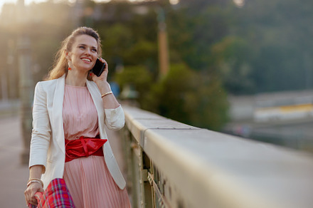happy woman in dress and jacket in city talking on phone, a Person Photo by Alliance Images