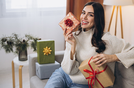 Beautiful happy woman unwrapping New Year or Christmas presents