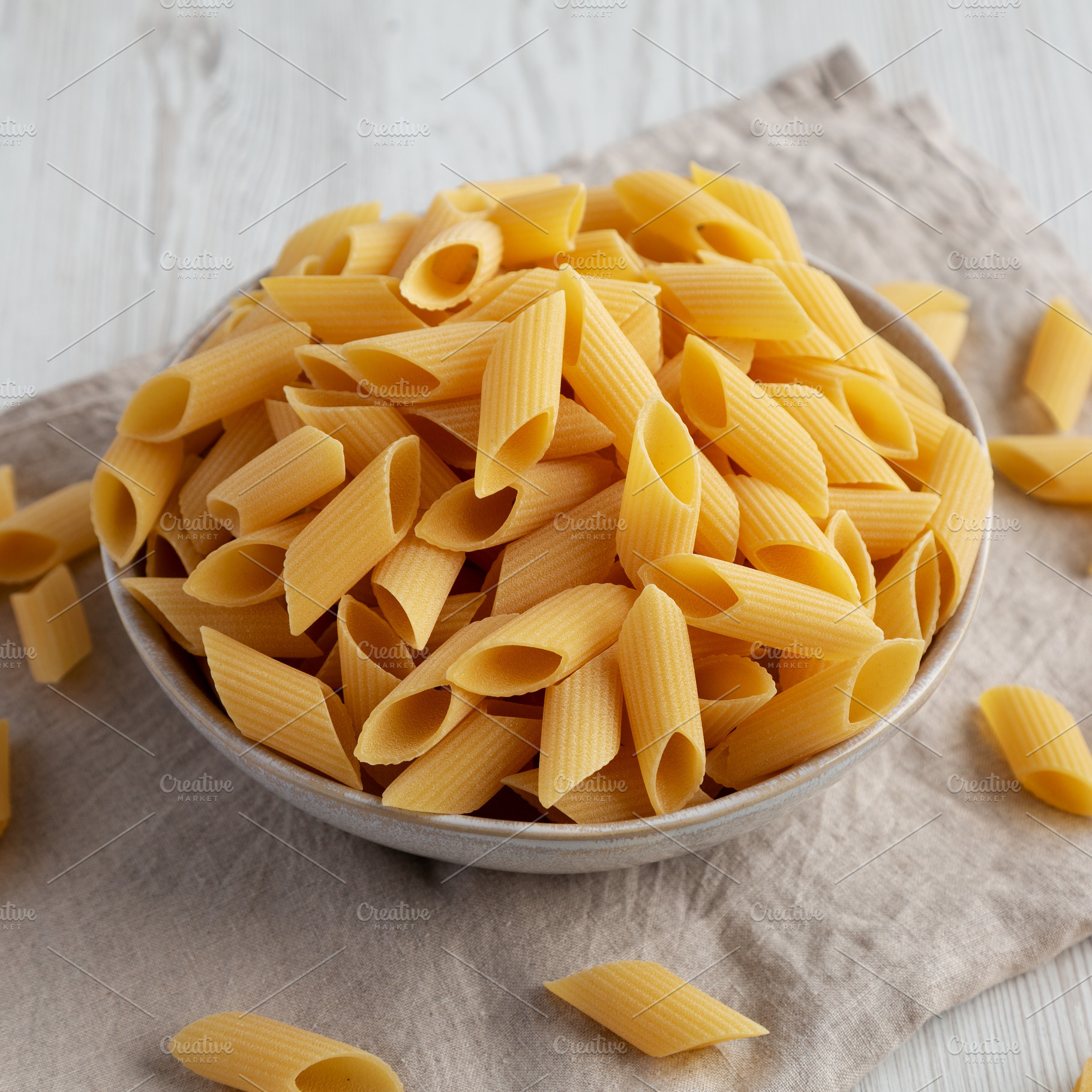 Raw Organic Dry Pennoni Pasta in a Bowl, side view., a Food & Drink Photo by LiudmylaChuhunova