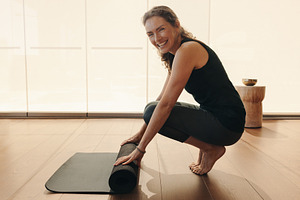Healthy senior woman rolling up an exercise mat at home, a Person Photo by Jacob Lund