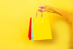 Close-up of a hand holding vibrant shopping bags against a brigh, a Beauty & Fashion Photo by Ales Munt