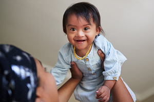 Happy, baby and child mom care of a woman holding a kid in the air feeling happiness at a house. Happiness and smile of a young toddler face from India in a home spending quality time with a mother, a Photo by Peopleimages.com