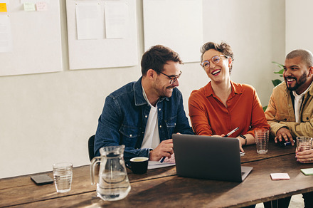 Smiling businesspeople having a discussion using a laptop in an