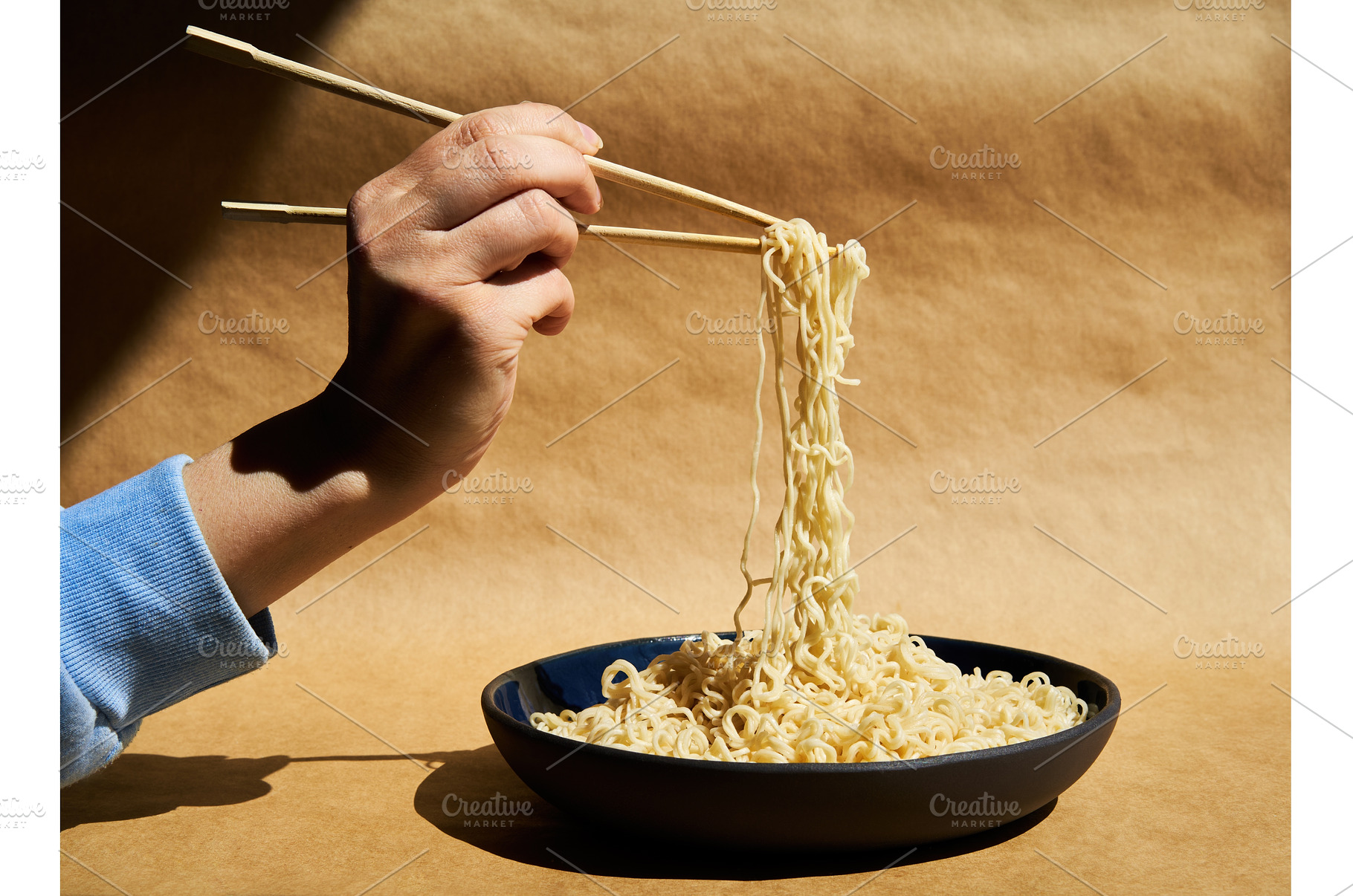 Woman hand holding chopsticks with, a Food & Drink Photo by Gladkov photography