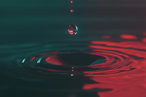 A close-up view of water droplets falling into a pool of water, creating ripple, a Photo by Textures & Backgrounds