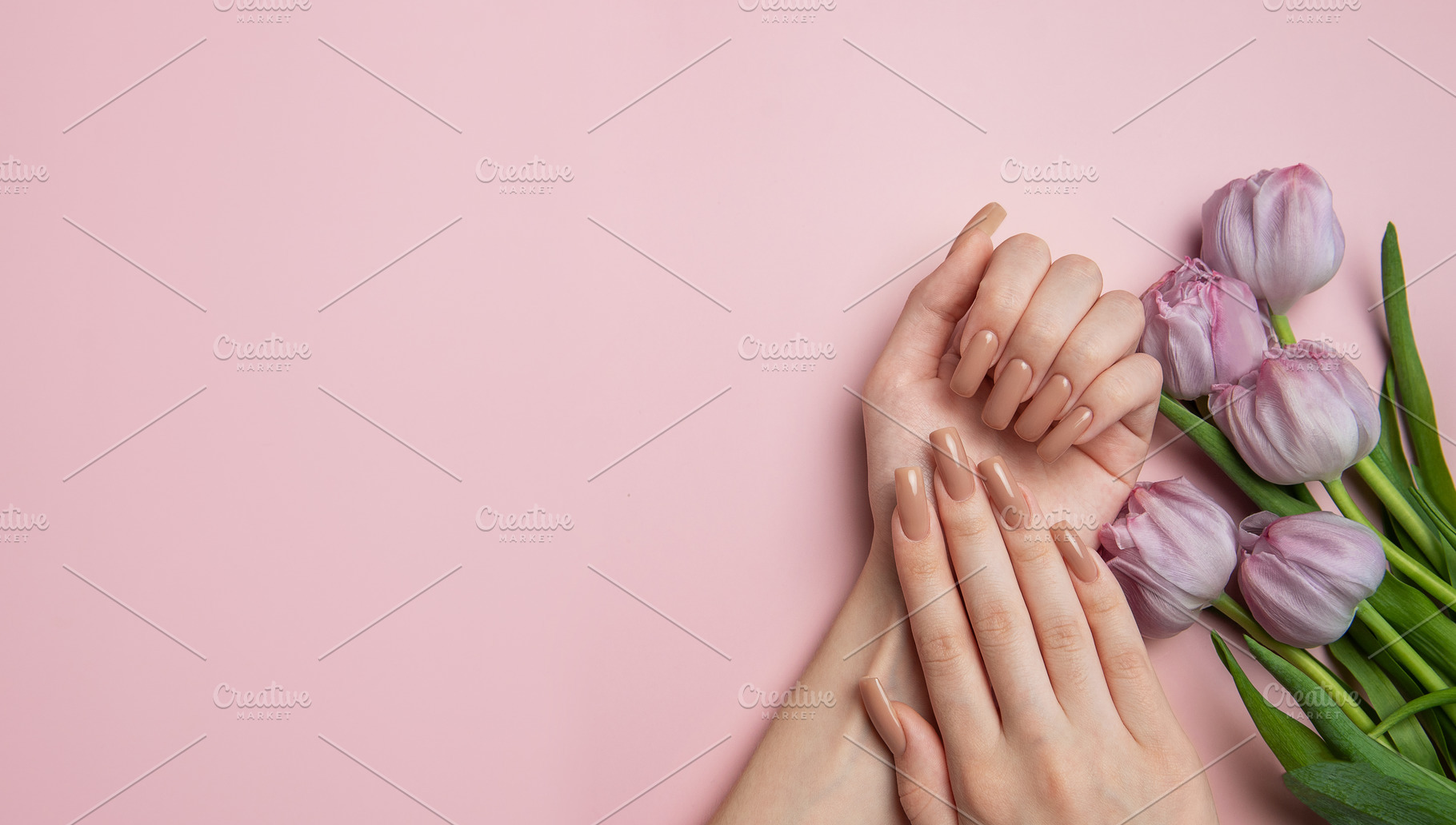 Woman showing nude manicure and purple tulips on pink background, a Beauty & Fashion Photo by Olena Rudo