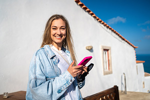 Happy woman holding smartphone at outdoor restaurant during summer, a Person Photo by andreonegin market