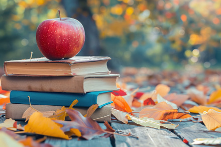 A red apple sits atop a stack of books on a wooden surface, surrounded by autum, a School & Education Photo by Textures & Backgrounds