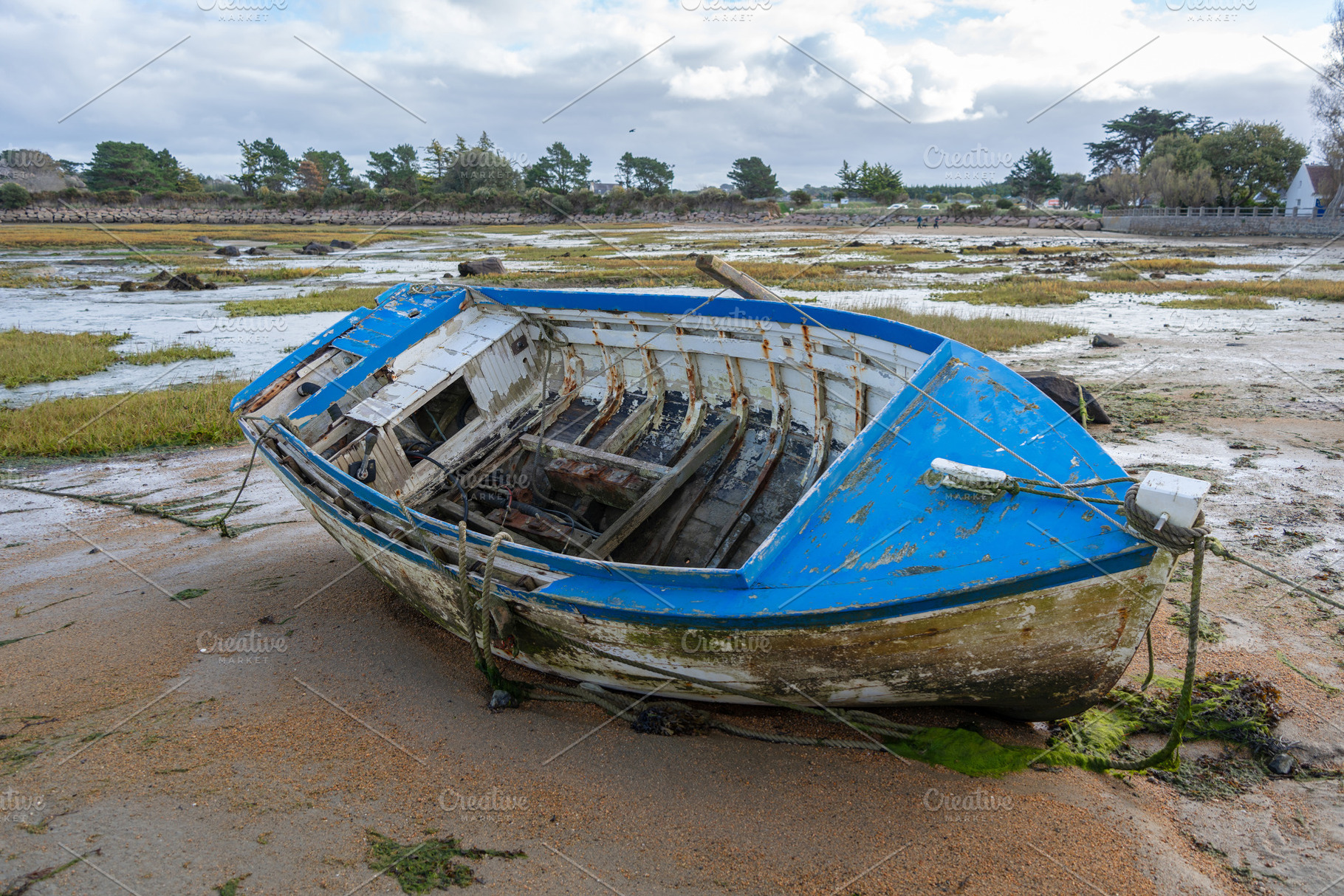 Abandoned blue boat stranded on tidal flats in Tregastel, France, a Transportation Photo by GoodGoods