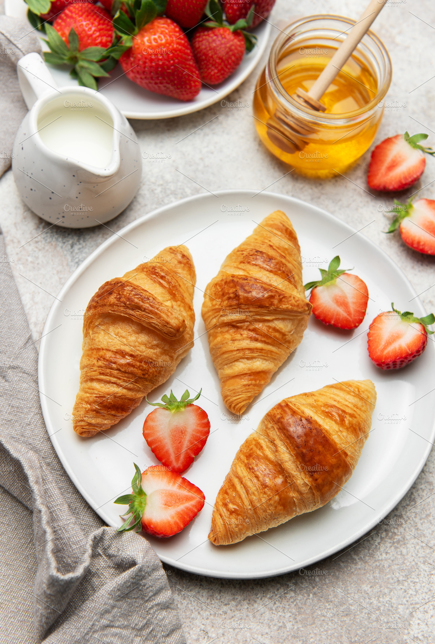 Delicious french breakfast with croissants, strawberries, honey, a Food & Drink Photo by Olena Rudo