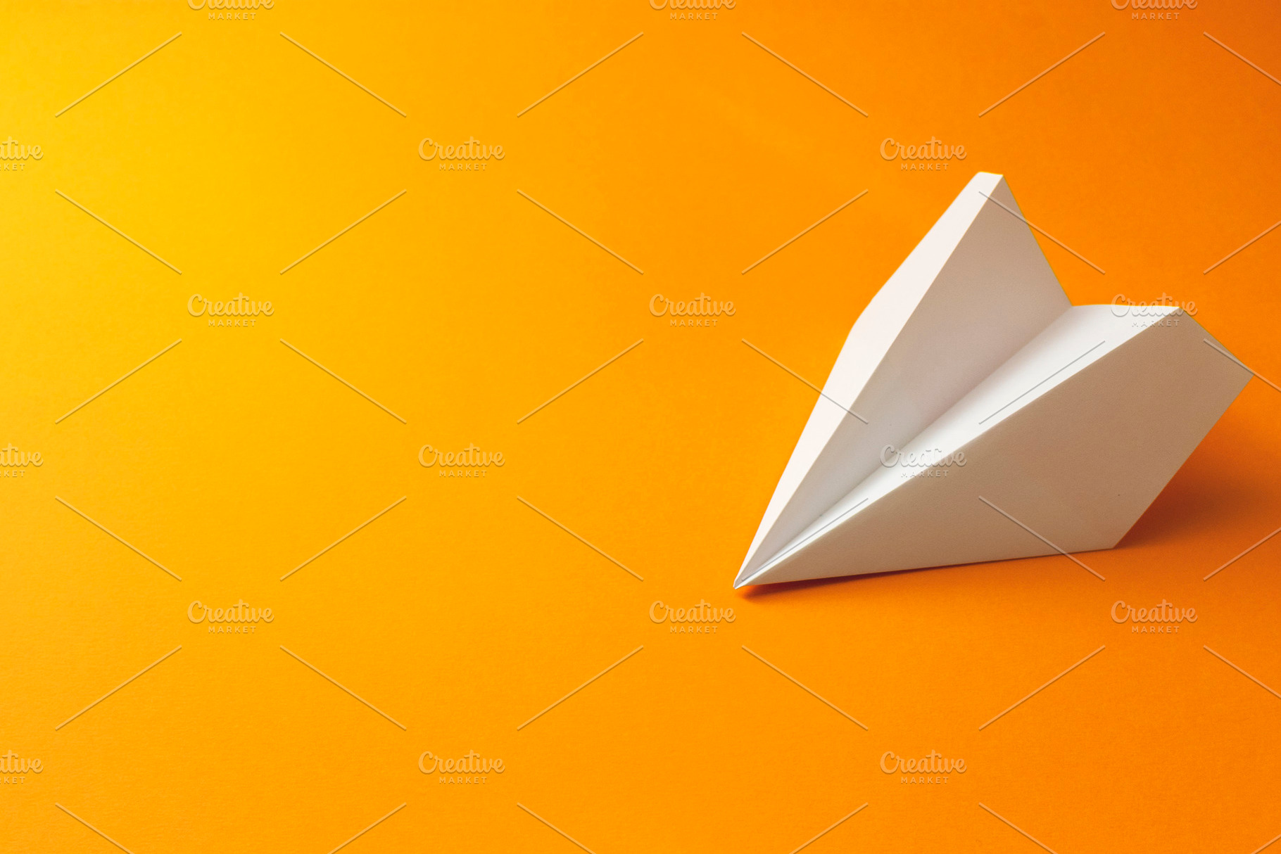 Paper plane on an orange background, an Abstract Photo by Ti-Di