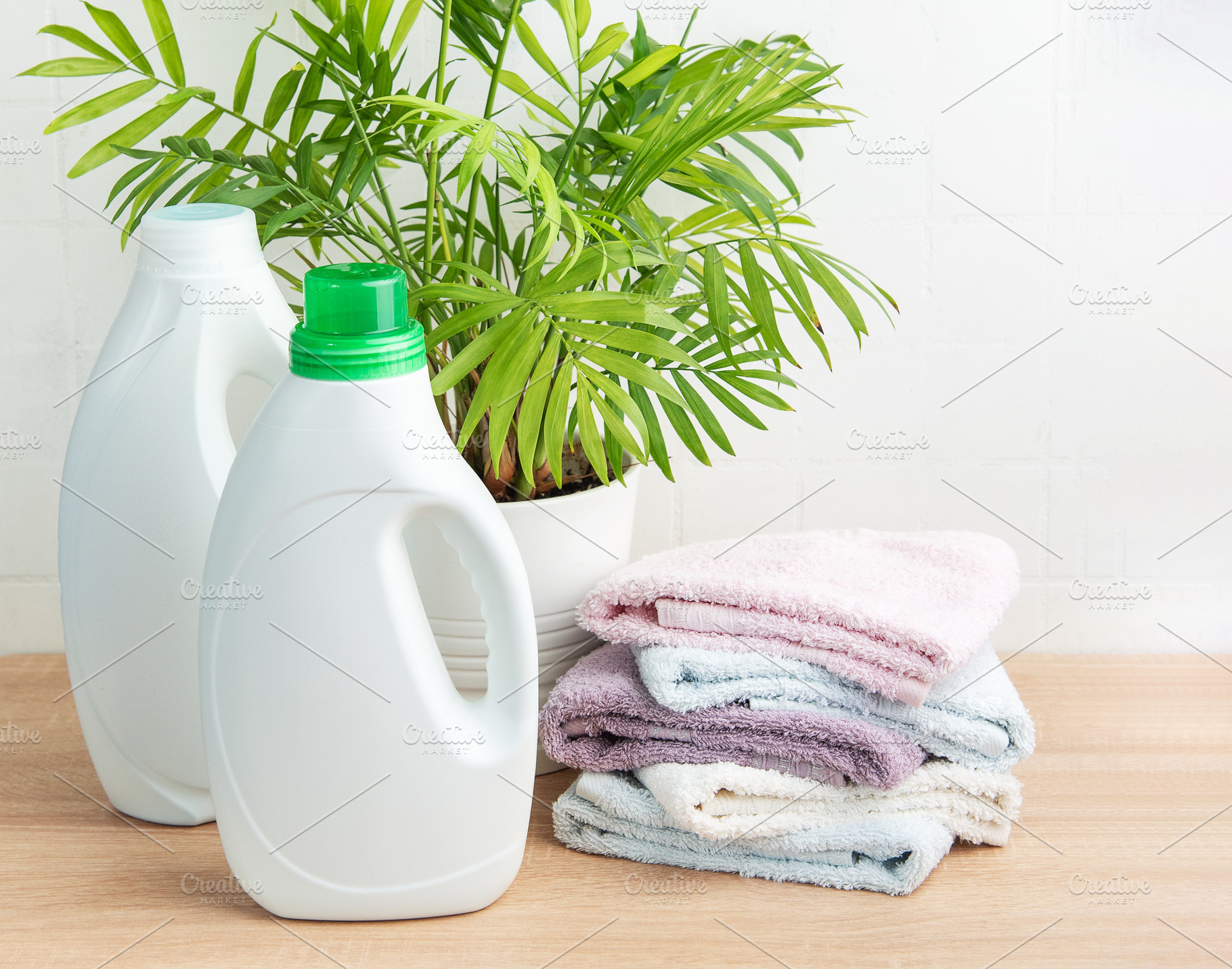 Laundry cleaning products with folded towels and plant, an Industrial Photo by Olena Rudo