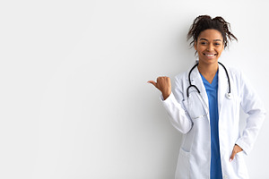 Portrait of black doctor smiling pointing at copy space, a Photo by Prostock-Studio
