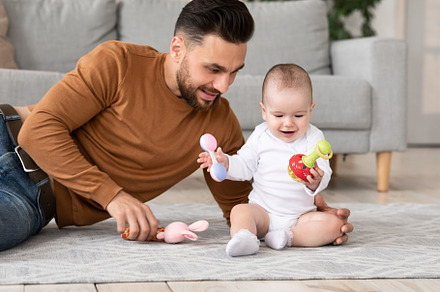 Dad Playing With Little Baby Toddler Holding Toys Sitting Indoors, a Background Photo by Prostock-Studio