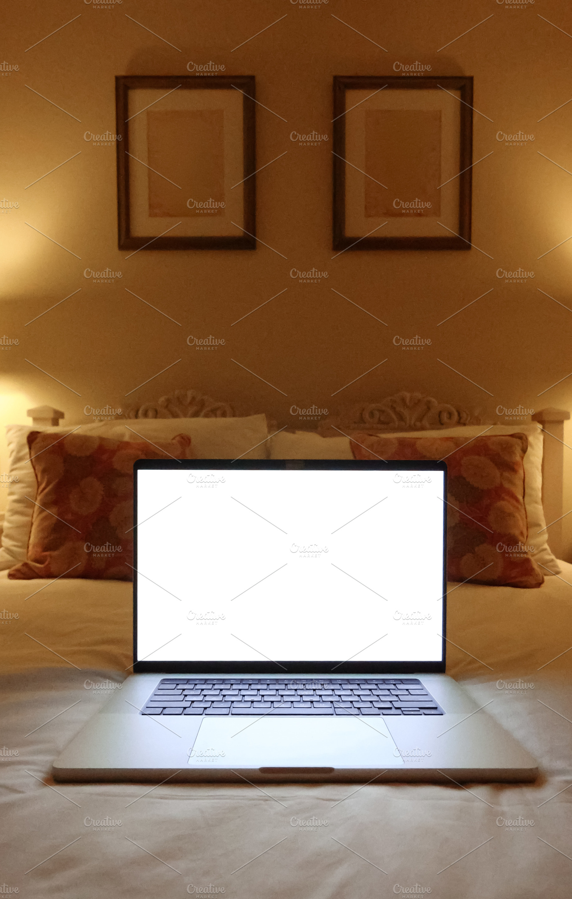 Laptop with a blank white screen resting on a bed in a cozy bedroom, featuring, a Photo by Studio ANNA