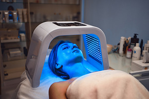 A young woman takes care of her skin with an LED mask in a beauty salon., a Beauty & Fashion Photo by Rov.7