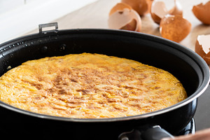 Hand holding frying pan with Spanish potato omelette, a Photo by etorres69