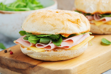 Two homemade sandwiches with ham, cheese and arugula on a concrete table., a Food & Drink Photo by Budarinphoto
