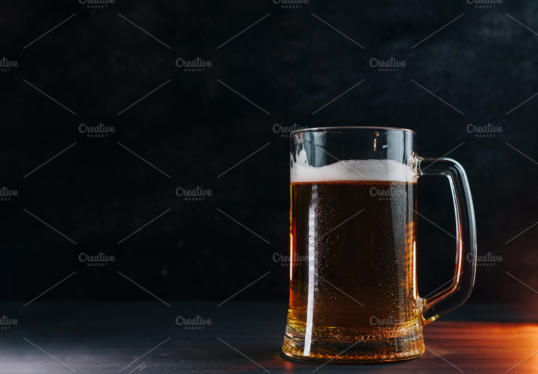 Light cold beer mug with water drops on a black table , backlight, a Food & Drink Photo by PavelKant