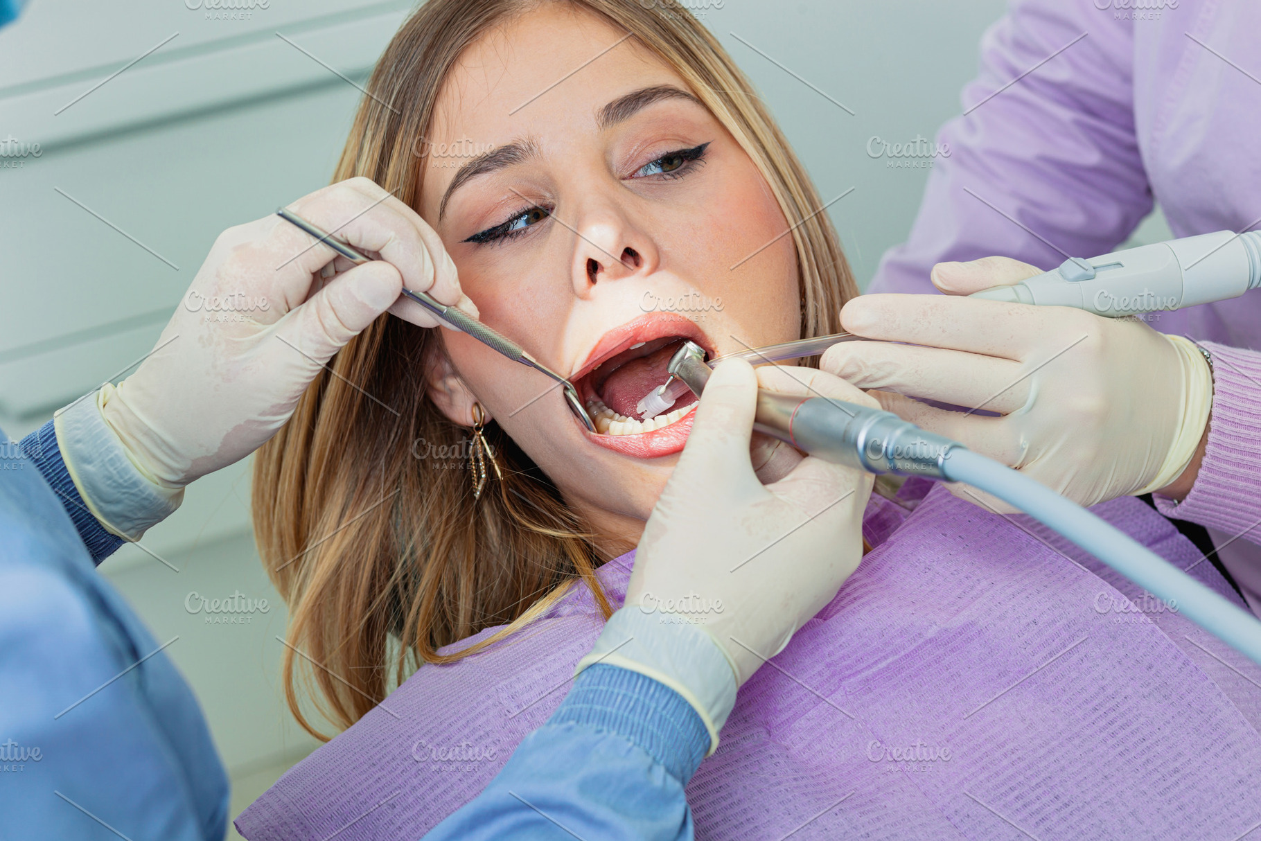 Dentist using dental drill and mirror while examining patient's teeth, a Health & Medical Photo by Antonio Gravante Market