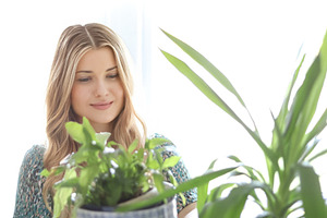 Blonde woman in a green dress looking at a houseplant with soft, a Person Photo by Studio ANNA