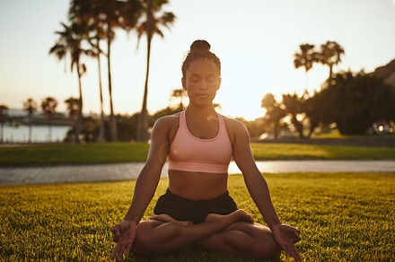 Fit young woman meditating while doing yoga in a park