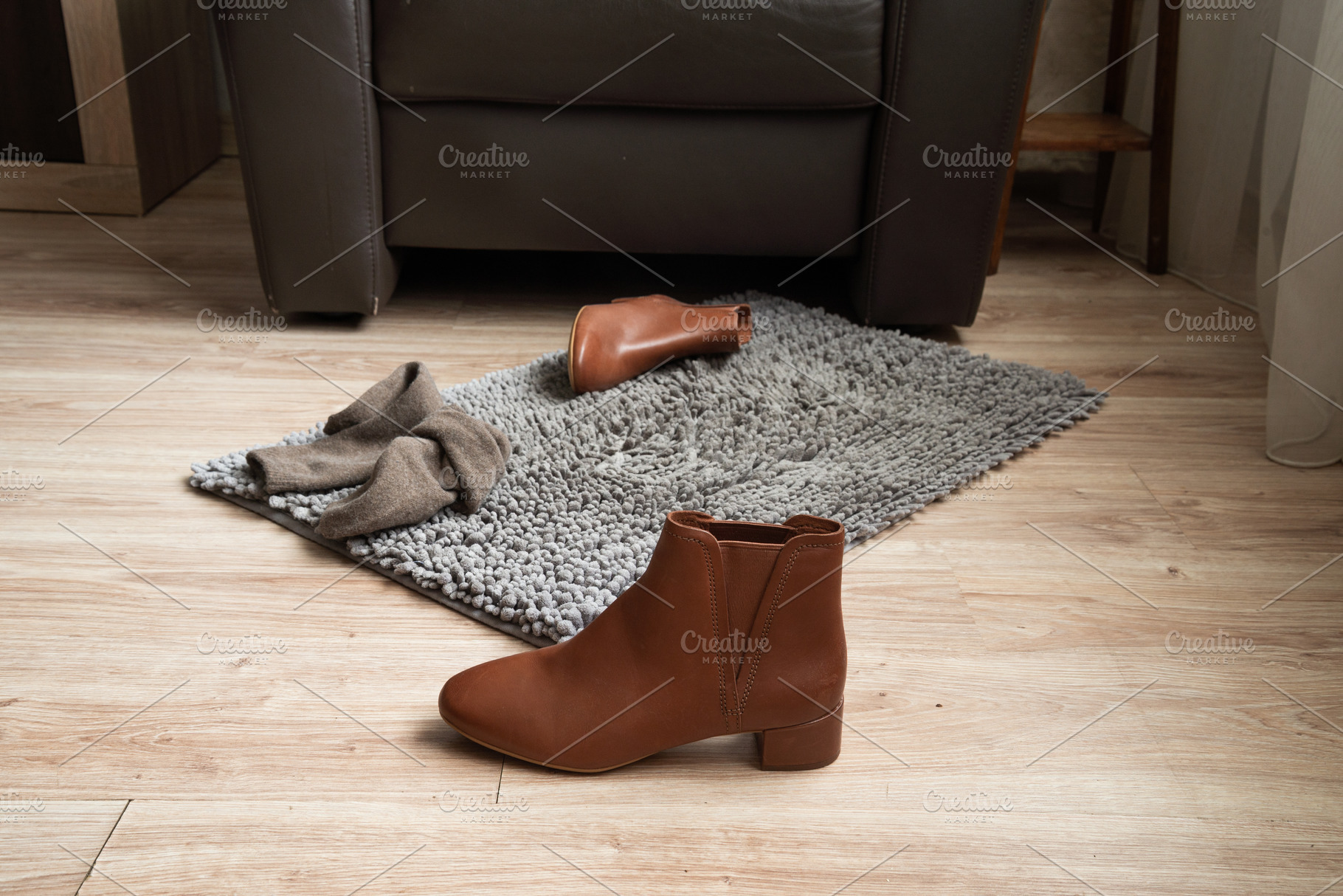 Brown leather ankle boot on floor near rug in home interior, an Industrial Photo by MDBildes