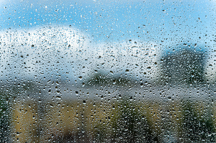 Raindrops on a window with a blue cloudy sky in the background., an Abstract Photo by Eugene_Photo