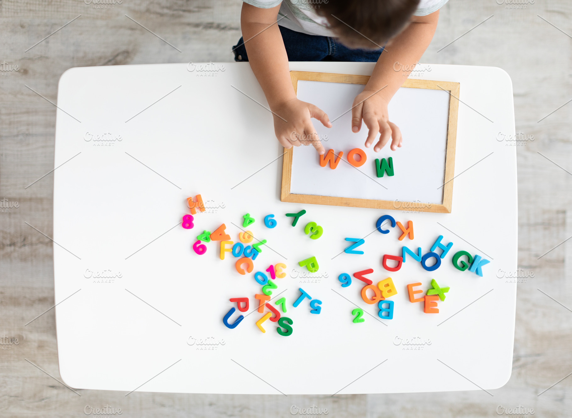 Early development and preparation for school. Top view of little kid making wor, a Photo by Prostock-Studio