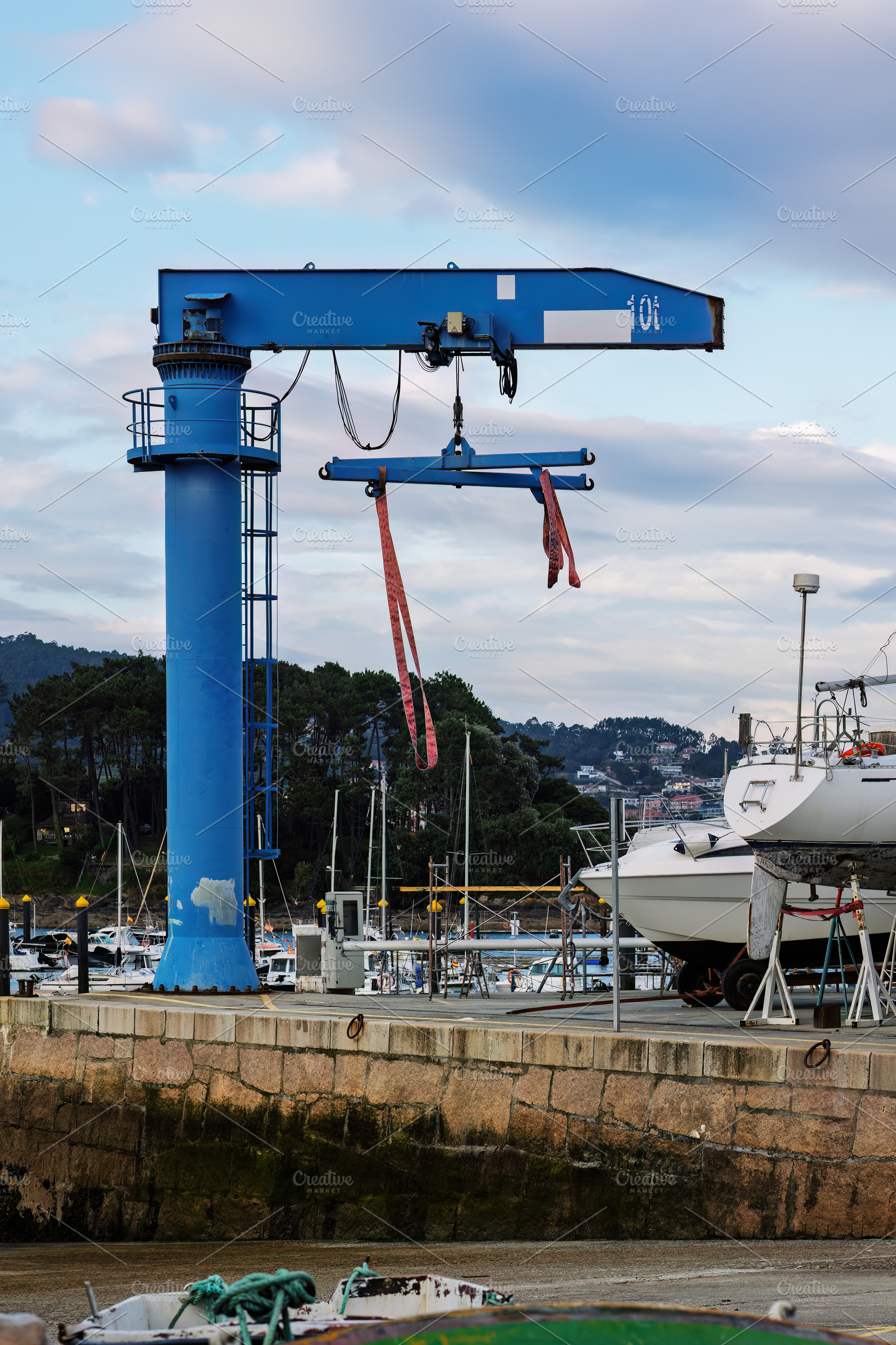 Blue dry dock crane in a marina with, an Industrial Photo by Perpis