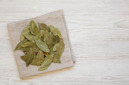 Raw Bay Leaves on a white wooden background, top view. Flat lay,, a Food & Drink Photo by LiudmylaChuhunova