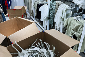 Cardboard Box Full of Hangers in Clothing Retail Store Interior, a Photo by AS photostudio
