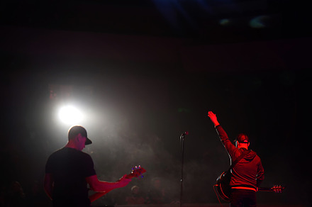 Rock band vocalist silhouette with the guitar singing to microphone with the ha