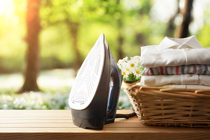 Iron showing sole with basket full of shirts in nature, a Technology Photo by Davizro's Market