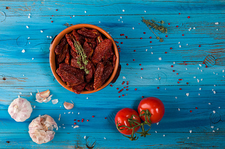 Mediterranean dried tomatoes inside a bowl on blue rustic wooden, a Food & Drink Photo by Bepslabor