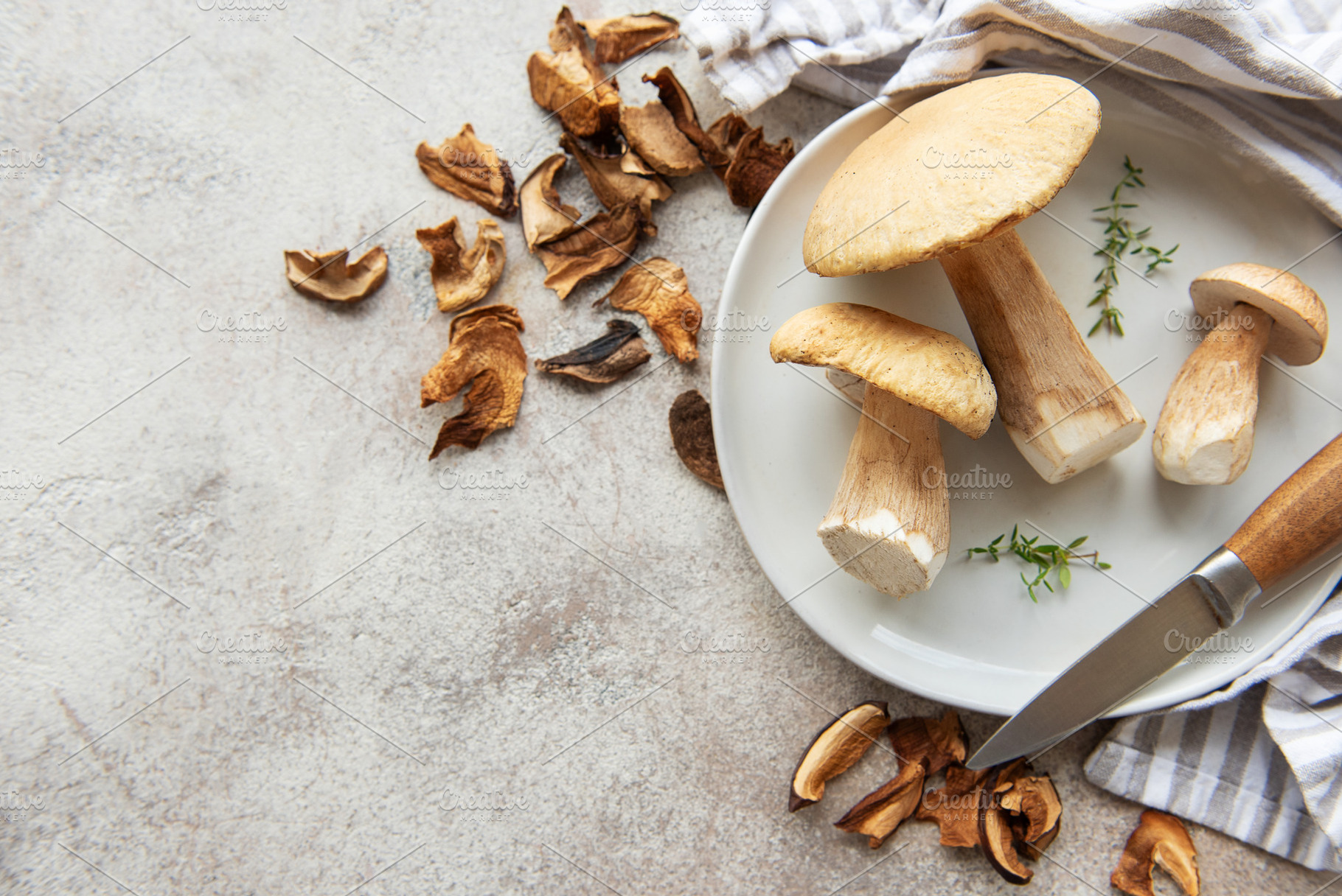 Fresh mushrooms on plate with dried mushrooms and knife, a Food & Drink Photo by Olena Rudo