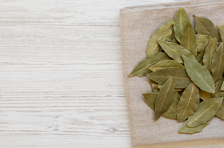 Raw Bay Leaves on a white wooden surface, top view. Flat lay, ov, a Food & Drink Photo by LiudmylaChuhunova