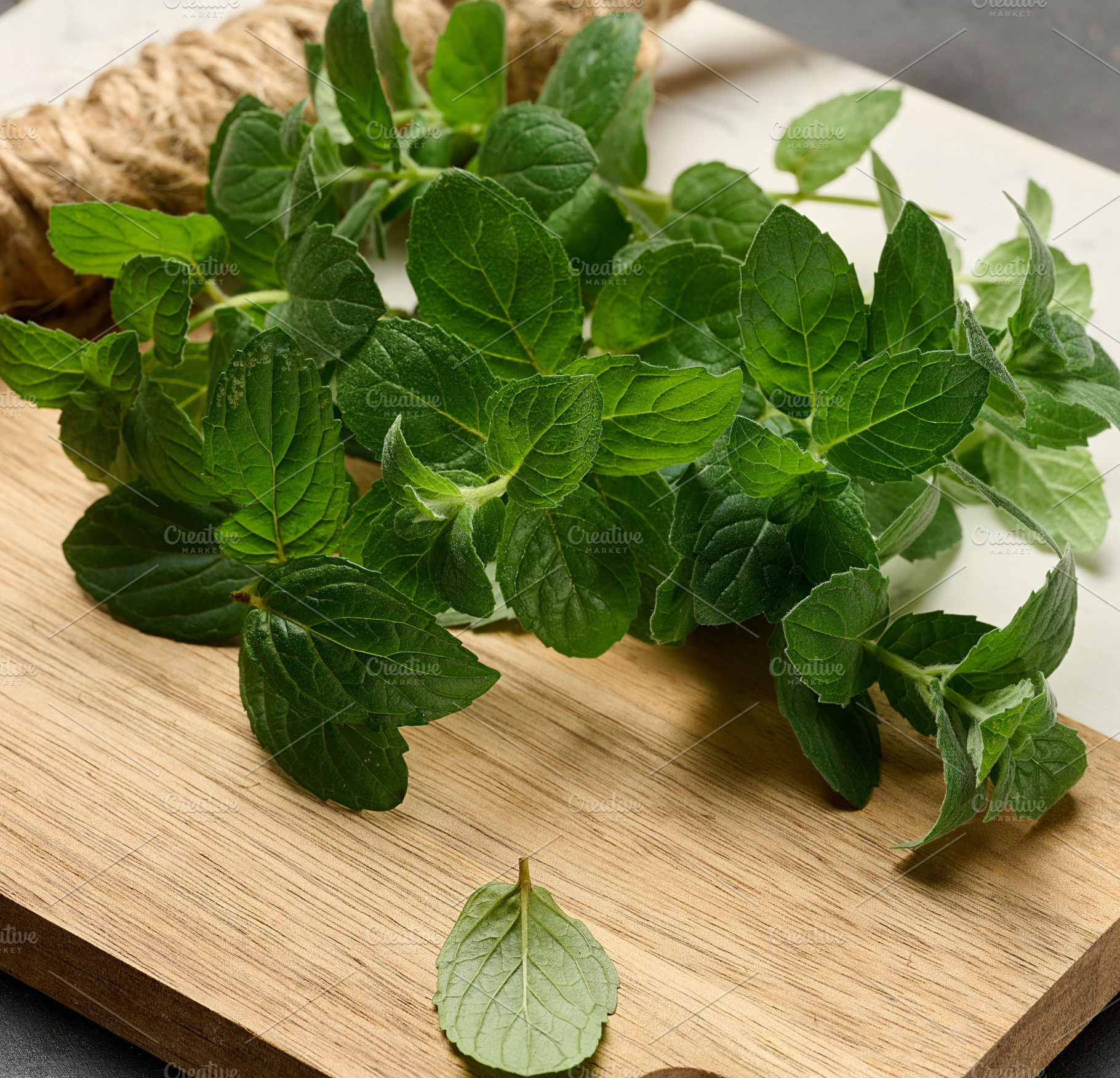 Fresh green mint sprigs lying on  wooden board, a Food & Drink Photo by ndanko