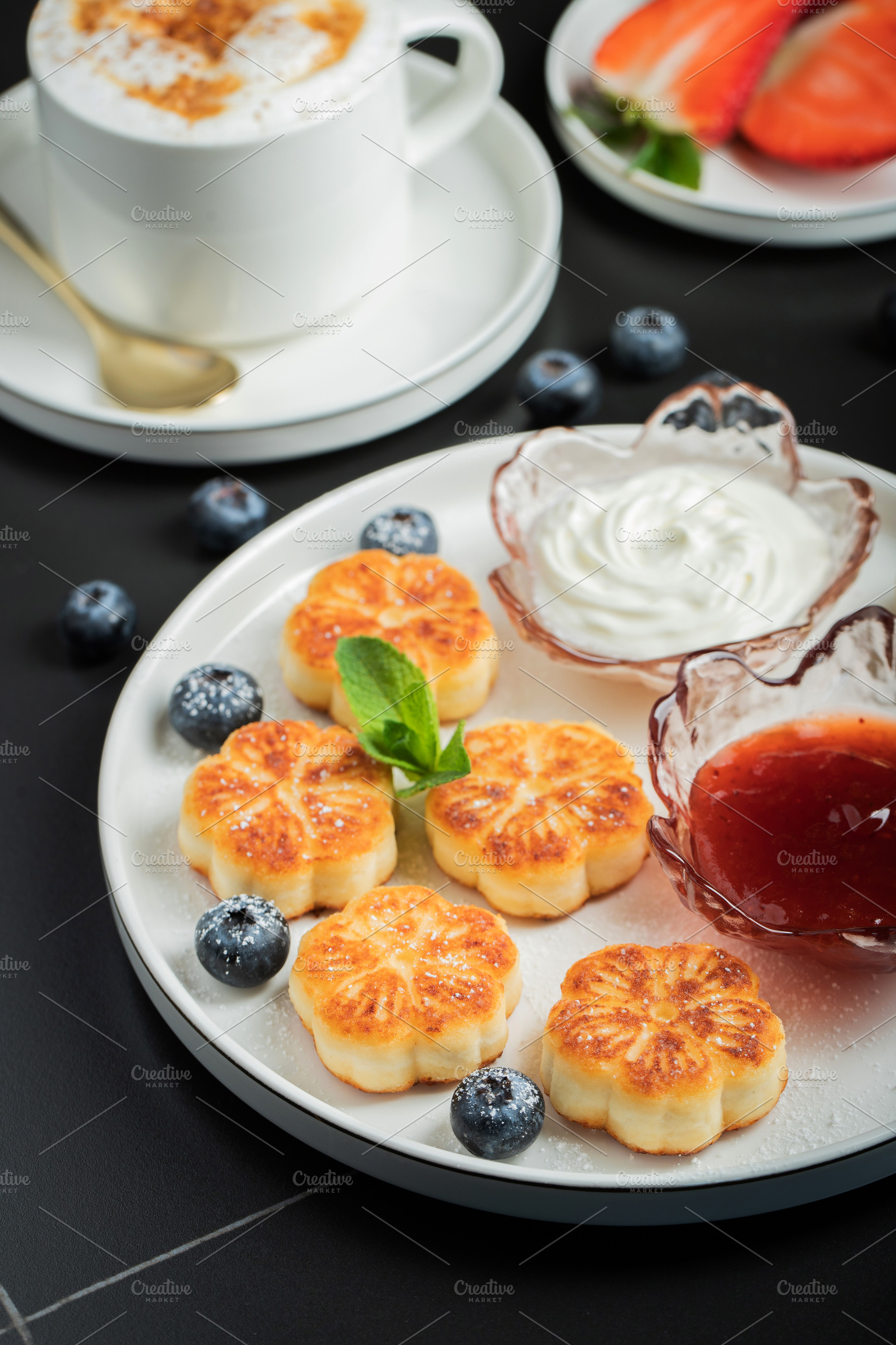 Cottage cheese pancakes, syrniki, curd fritters decorated with strawberry and r, a Food & Drink Photo by Budarinphoto