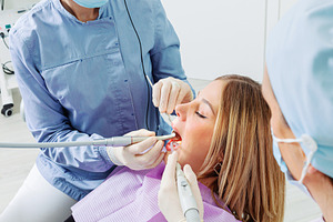 Dentist and assistant performing dental checkup on female patient, a Health & Medical Photo by Antonio Gravante Market