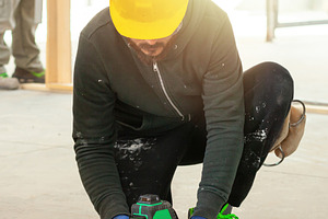 Construction worker using rotating laser level on tripod at construction site, an Industrial Photo by Antonio Gravante Market