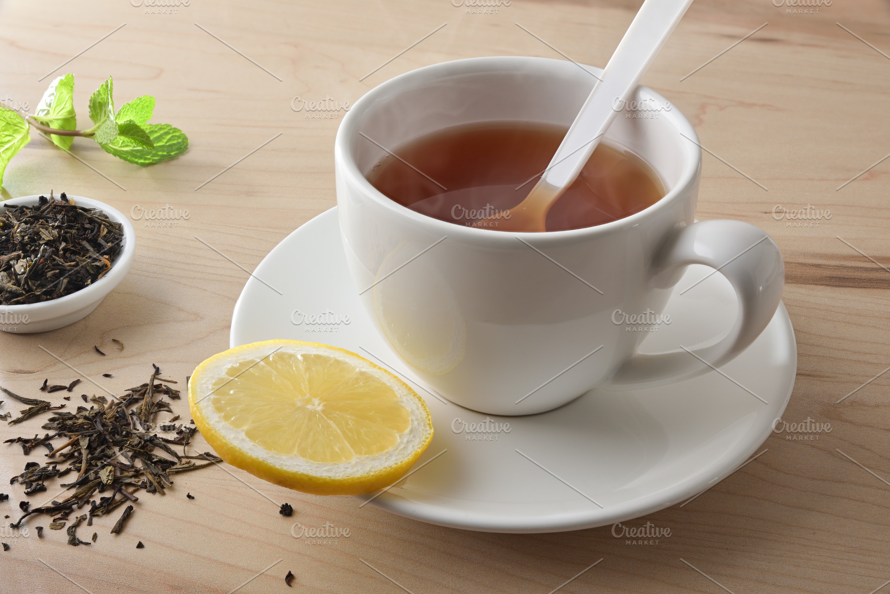 Tea with lemon in white ceramic cup on wooden table, a Food & Drink Photo by Davizro's Market