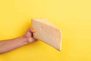 Close-up of a hand with yellow nails holding a large wedge of ch, a Food & Drink Photo by Ales Munt