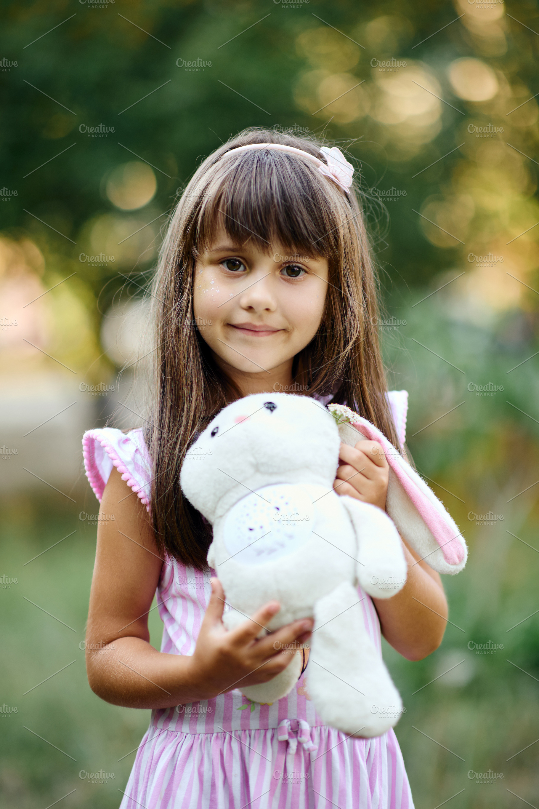 Portrait of a cute little girl smiling and holding a plush bunny toy., a Person Photo by Rohan Photography