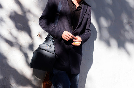Man leaning on a wall with headphones under dappled sunlight., a Person Photo by RF Images