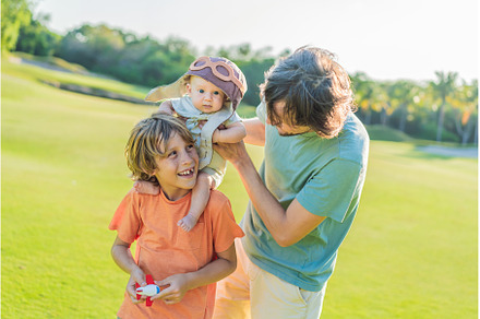 Father, son, and newborn on a meadow
