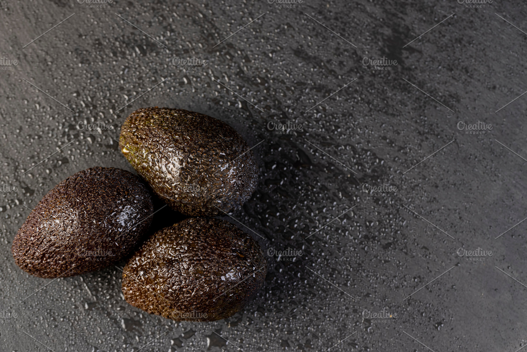 wet avocado fruits of small size on a black slate, ripe avocado fruit in drops, a Photo by MyPhotos