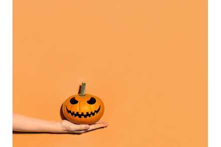 Halloween pumpkin in hand on orange, a Holiday Photo by Fascinadora