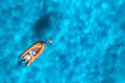 Aerial view of beautiful orange boat in blue sea at sunset, a Nature Photo by den-belitsky